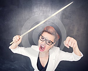 Angry screaming teacher with pointer on blackboard background