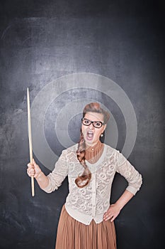 Angry screaming teacher with pointer on the chalkboard background