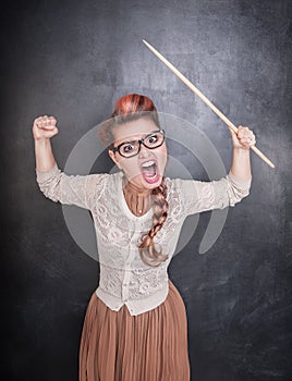 Angry screaming teacher with pointer on the chalkboard background