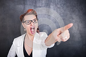 Angry screaming woman pointing out on blackboard background