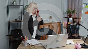 Angry senior business woman making phone call at office work annoyed boss talking mobile quarrel