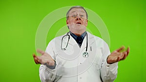 Angry senior doctor in white coat waves his hands, screams and swears loudly.