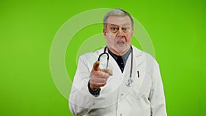 Angry senior doctor in white coat waves his hands, screams and swears loudly.