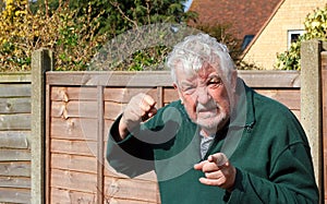 Angry senior or elderly man pointing and raising his fist.