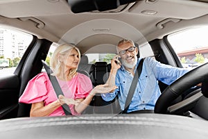 Angry senior woman shouting while car driver talking on phone