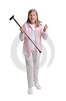 Angry senior woman with walking cane on white background