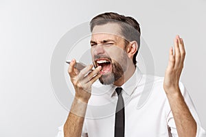 Angry and serious businessman talking on the phone over gray background