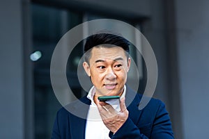 Angry and serious Successful Asian businessman explains information to employees using phone, speaks near office outside