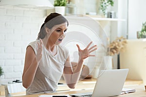 Angry shocked young woman looking at laptop screen, reading news