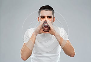 Angry shouting man in t-shirt over gray background