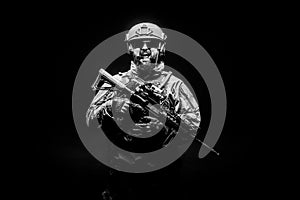 Angry soldier in uniform with a rifle screaming at night, commando in stress on a black background, portrait of a ranger