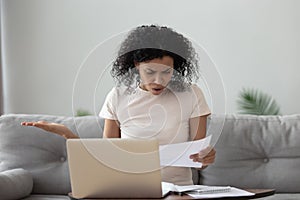 Angry stressed african girl reading bad news in mail letter