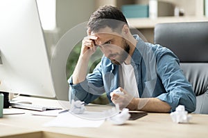 Angry Stressed Businessman Crumpling Paper While Sitting At Desk In Office