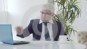 Angry strict businessman scolding employees in wireless chat. Portrait of dissatisfied senior Caucasian CEO using online
