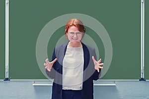 Angry teacher in a suit at the blackboard, copy space. Female school teacher, close-up