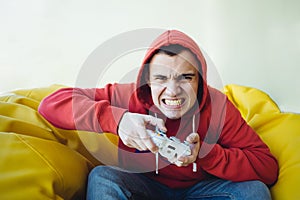 Angry teen gamer emotionally plays a joystick on the console. Focused view of the camera.