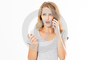 Angry teen woman in grey shirt shouting on smartphone over white background, bad news reading