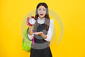 Angry teenager girl, upset and unhappy negative emotion. Back to school. Teenage school girl with bag hold clock alarm