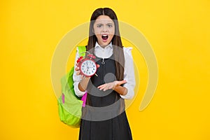 Angry teenager girl, upset and unhappy negative emotion. Back to school. Teenager school girl with backpack hold clock