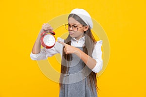 Angry teenager girl, upset and unhappy negative emotion of teen student girl with clock isolated on yellow background