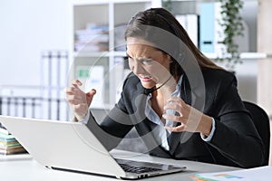 Angry telemarketer woman looking at laptop at office