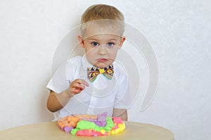 Angry toddler boy playing with kinetic pasticine, a great activity to develop fine motor skills