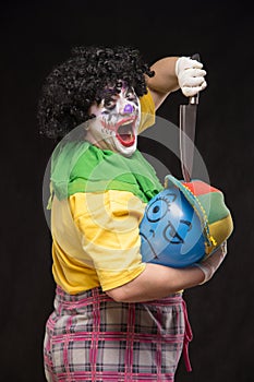 Angry ugly clown wants to kill a balloon in the cap