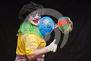 Angry ugly clown wants to kill a balloon in the cap