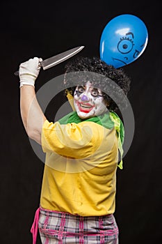 Angry ugly clown wants to kill a balloon in the cap