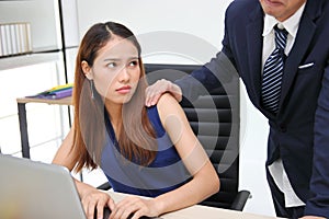 Angry unhappy Asian secretary woman looking hand`s boss touching her shoulder in workplace. Sexual harassment in office