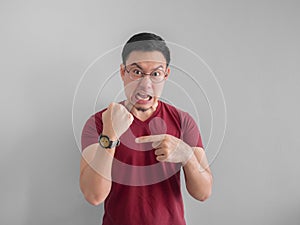 Angry and unpleasant face of man is looking at his watch waiting