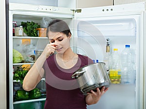 Angry and upset housewife looking into pot with foul meal