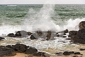 Angry waves crash over rocks on the coast during a summer storm