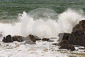 Angry waves crash over rocks on the coast during a summer storm