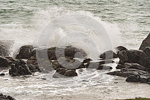 Angry waves crash over rocks on the coast during a summer storm