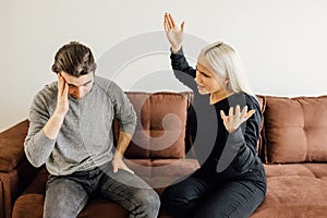 Angry wife cries out to her husband, who covers his ears with his hands.