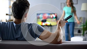 Angry wife quarreling with husband watching football game, conflict in relations