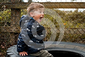 An angry wild child boy screams at the camera, ready to fight. Tantrums and disobedience crisis of three years and self