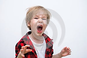 An angry wild child screams at the camera, ready to fight. Tantrums and disobedience crisis of three years and self-isolation,