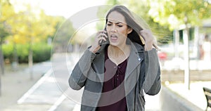 Angry woman arguing on phone in a park