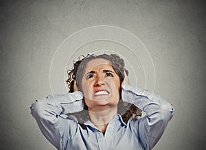 Angry woman covering ears looking up stop loud noise