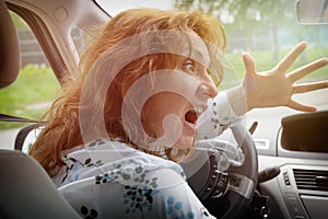 Angry woman driver screaming while driving a car