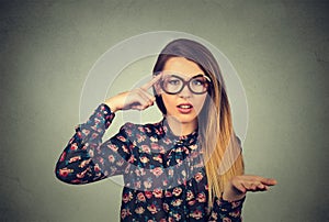 Angry woman gesturing with her finger against temple asking are you crazy?