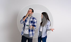 Angry woman gesturing and looking at ecstatic gamer man blowing kiss while playing video game over mobile phone. Serious