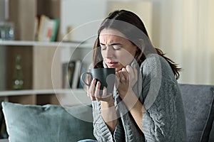 Angry woman getting cold holding coffee mug at home