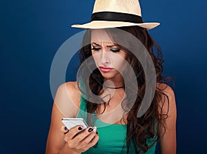 Angry woman in hat looking and reading sms on mobile phone in st