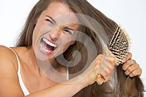 Angry woman having hard time combing hair