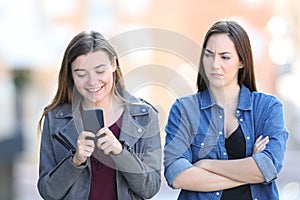 Angry woman with her friend who is using phone photo