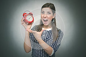 Angry woman with red alarm clock. Oversleep. Late at work or school lesson. photo