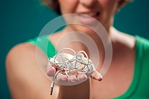 Angry woman holding tangled earphone trying to untangle it. People and technology concept